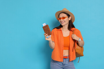 Wall Mural - Happy traveller with backpack and passport on light blue background. Space for text