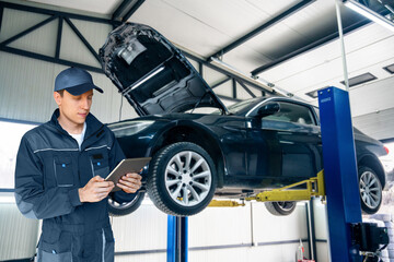 Poster - Serviceman with digital tablet on the background of the car in the car service.