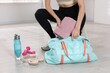 © New Africa - Woman packing her gym bag at home, closeup