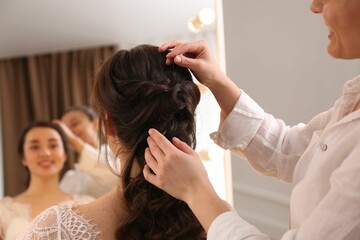 Wall Mural - Stylist working with client in salon, making wedding hairstyle