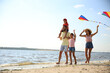 © New Africa - Happy parents and their children playing with kites on beach near sea. Spending time in nature