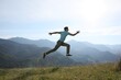© New Africa - Sporty man running on grassy hill in mountains
