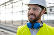 © zinkevych - Smiling caucasian bearded engineer in protective glasses at the construction site