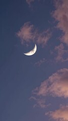 Wall Mural - a serene crescent moon against a pastel sky with soft clouds, captured from a low-angle, perfect for