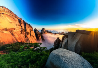 Poster - Breathtaking China landscape view at sunrise, featuring majestic mountains shrouded in fog, with vibrant sky and rocky terrain. Scenic and tranquil nature.
