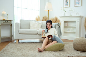 Young Asian woman enjoying reading book in living room at home