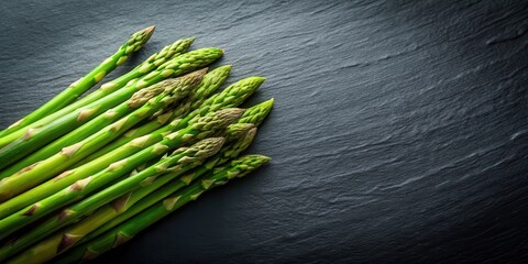 Poster - A vibrant bunch of fresh green asparagus spears arranged on a dark slate surface