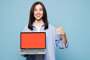 Young IT woman she wears shirt casual clothes hold use work on laptop pc computer with blank screen workspace area show thumb up isolated on plain pastel light blue cyan background. Lifestyle concept.