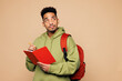 © ViDi Studio - Young smart boy student he wear green casual clothes backpack bag hold books write down in exercise book notebook diary notes isolated on plain beige background High school university college concept