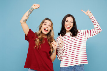 Wall Mural - Young fun couple two friends women wear red casual clothes together point index finger overhead on area do winner gesture isolated on pastel plain light blue cyan background studio. Lifestyle concept.