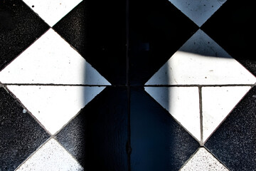 Wall Mural - Shadow Play on Checkerboard Floor: A dramatic interplay of light and shadow on a black and white checkered floor creates a captivating geometric pattern.