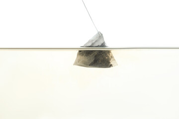 Wall Mural - Putting tea bag into glass cup on white background, closeup