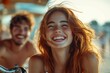© piyumal - A redhead woman laughs joyfully with a man blurred in the background, enjoying a sunny day outdoors.
