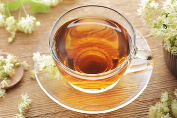 Wall Mural - Linden herbal tea in a glass cup with flowers on wooden rustic background, closeup, sleep and relax drink, natural medicine and naturopathy concept