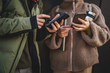 Wall Mural - close up on male and female hands use mobile phone in front black wall