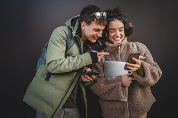 Wall Mural - young couple stand and use cellphone in front black wall outdoor