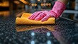 © Iurii - Bright pink glove scrubbing a granite countertop with a yellow microfiber towel