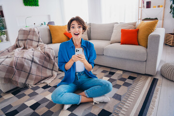 Wall Mural - Photo of cheerful adorable excited girl sitting on floor in apartment winning jackpot gambling betting esport