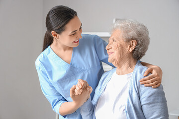 Physical therapist helping senior woman to walk at home