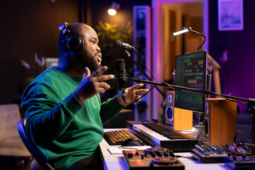 Poster - Young singer recording his new composed song on microphone, editing the tracks with mixing console and professional software. Artist manipulating sounds to create a good soundtrack.