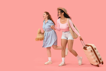 Wall Mural - Beautiful young happy female friends with summer bags and suitcase on pink background