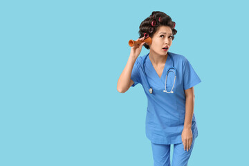 Poster - Female Asian doctor with hair curlers and stethoscope on blue background