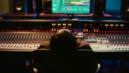Aufkleber - Sound designer relaxing on studio chair after mixing and mastering tracks, finishing his musical project in control room. African american audio expert producing new songs. Camera B.