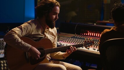 Poster - Rockstar recording music on his guitar in professional studio, creating new music for his album in control room. Artist composer producing tracks on electro acoustic guitar. Camera A.
