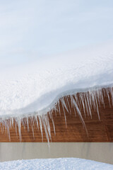Wall Mural - long icicles hanging from a snow-covered building roof in winter