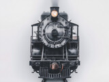 Front and side views of vintage steam locomotives, showcasing detailed metalwork, large headlights, and classic industrial design.