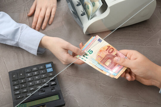 Wall Mural -  - client giving euro banknotes to cashier at table in money exchange, closeup