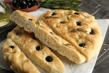 Wall Mural - Slices of delicious focaccia bread with olives and rosemary on table, closeup