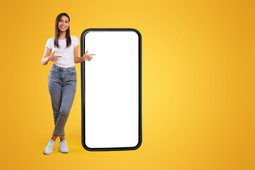 Aufkleber - Mobile App Advertisement. Full Body Length Of Happy Woman Showing Pointing At Big Huge White Empty Smartphone Screen Standing Over Orange Studio Background. Check This Out, Cellphone Display Mock Up