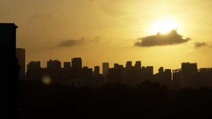 Poster - Silhouette of a skyline and trees under a yellow sunset sky with clouds