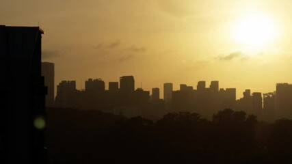 Poster - Silhouette of a skyline and trees under a yellow sunset sky with clouds