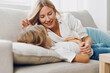 © SHOTPRIME STUDIO - Mother and daughter sharing a cozy moment on the couch, smiling and bonding in a warm living room setting