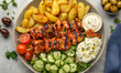 © Swaha - Delicious grilled chicken souvlaki with potato wedges, fresh cucumber salad, and creamy tzatziki sauce. Perfect for a healthy and flavourful meal.