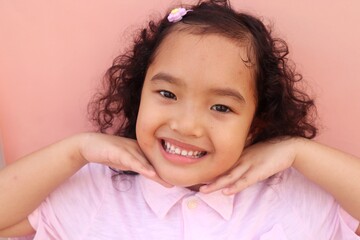 Closeup of Asian face, smiling toddler girl showing her healthy white teeth.