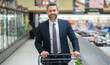 © Volodymyr - Businessman in a suit shopping in the supermarket. The businessman with shopping cart selecting fresh groceries. The man pushes his shopping cart down the aisles. Manager shopping in the grocery store
