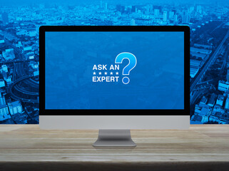 Wall Mural - Ask an expert with star and question mark sign icon on desktop modern computer monitor screen on table over city tower, street, expressway and skyscraper, Technology communication online concept