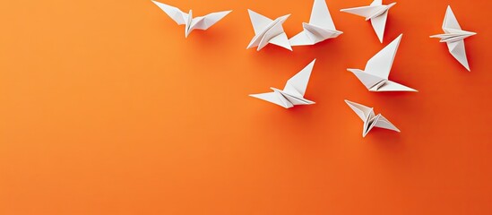 Fototapete - Elegant white origami birds scattered on vibrant orange background with soft shadows creating a serene flat lay composition