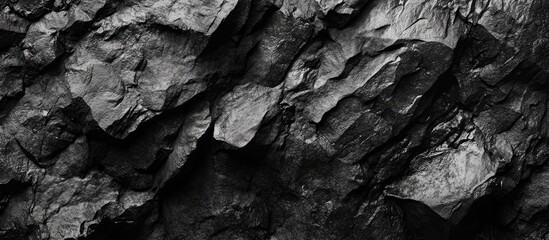 Poster - Close-up of rough black volcanic rock texture with sharp edges and deep crevices showcasing a dramatic mountain surface in high contrast lighting