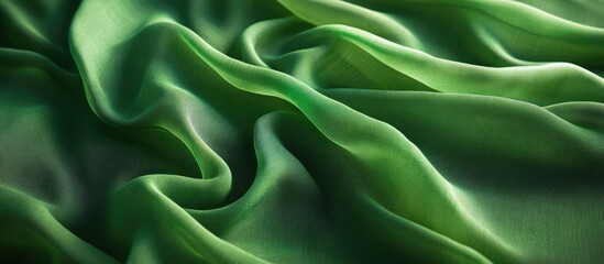 Poster - Elegant green silk fabric with soft folds and subtle sheen, showcasing rich texture and fluidity on a dark background.