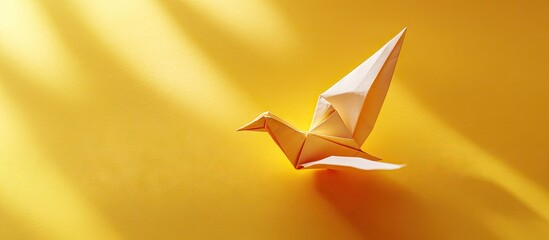 Leinwandbilder - Yellow origami bird positioned right side against vibrant yellow background with soft lighting creating shadows and space for text on left