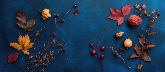 Aufkleber - Assorted autumn leaves and fruits arranged artistically on a deep blue background, featuring vibrant reds, yellows, and contrasting browns.