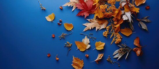 Fototapete - Autumn leaves and flowers in warm hues of orange, yellow, and red scattered on a vibrant blue background, creating a seasonal still-life composition.