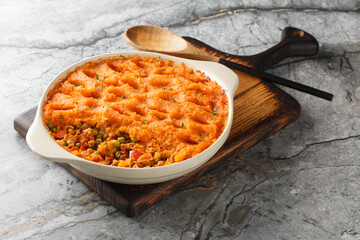 Wall Mural - Baked Sweet Potato Shepherd's Pie with mince and fresh vegetables close-up in baking dish on wooden board. Horizontal