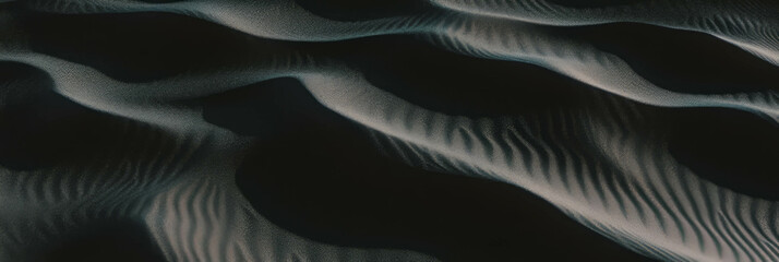 Poster - Black sand dune with rippled surface showcasing intricate windblown patterns and soft lighting