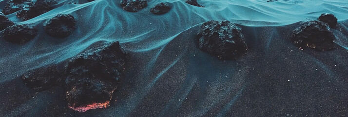 Poster - Textured black sand with porous volcanic rock under soft shadows