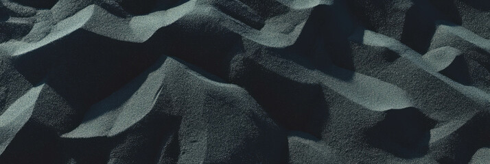 Poster - Coarse black volcanic sand texture revealing sharp angles and deep shadows in natural formation